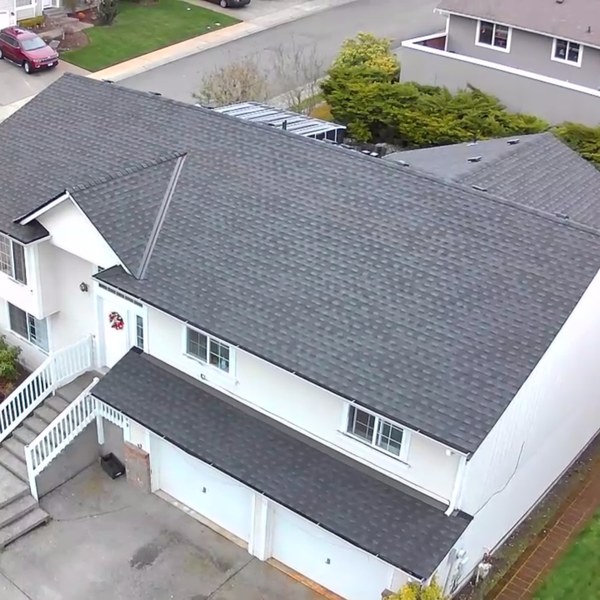 Drone view of a finished dark shingle reroof on a white two story house